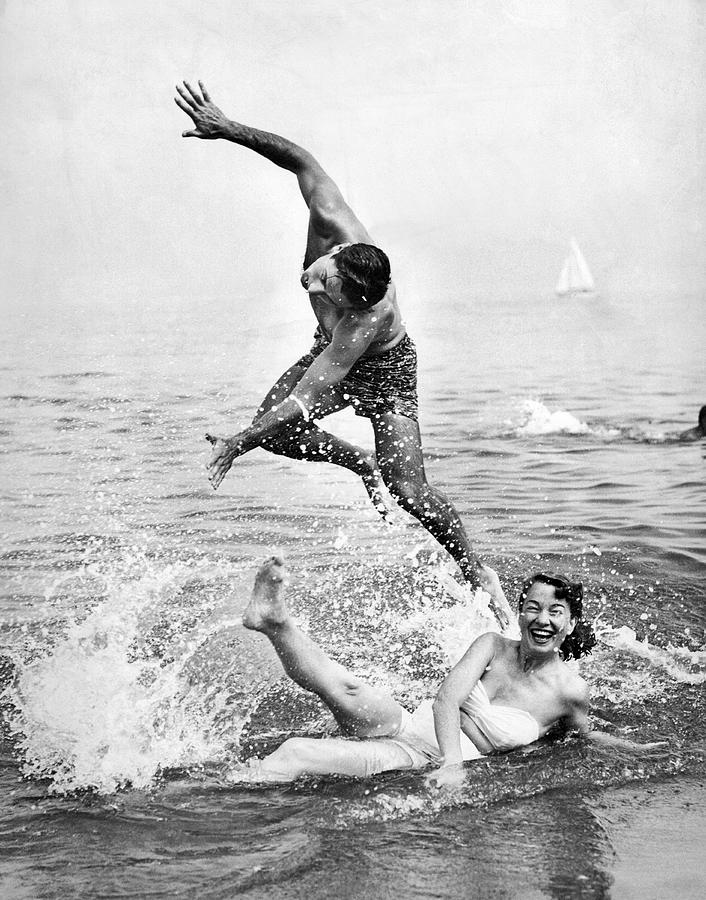 Black And White Photograph - Couple Frolics In The Surf by Underwood Archives