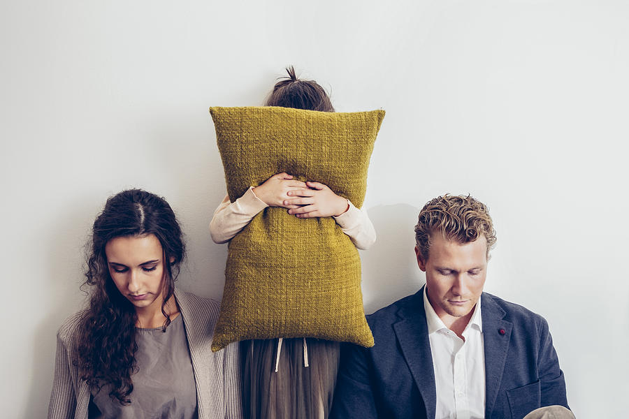 Couple having relationship conflict with their daughter hiding her face behind cushion Photograph by Westend61