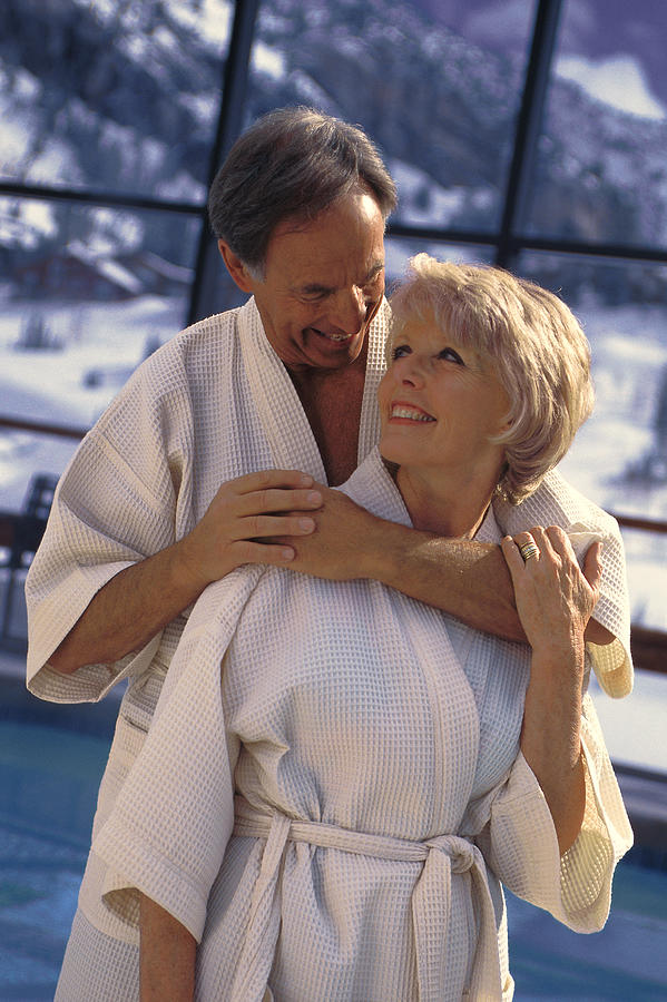 Couple hugging near indoor pool at resort Photograph by Comstock