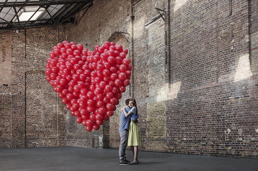 Couple in warehouse with heart made of balloons Photograph by Anthony Harvie