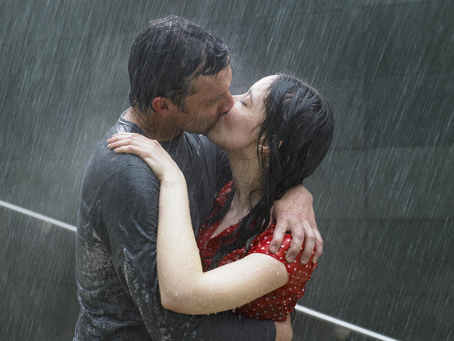 Couple kissing in rain, side view, close-up Photograph by Michael Blann