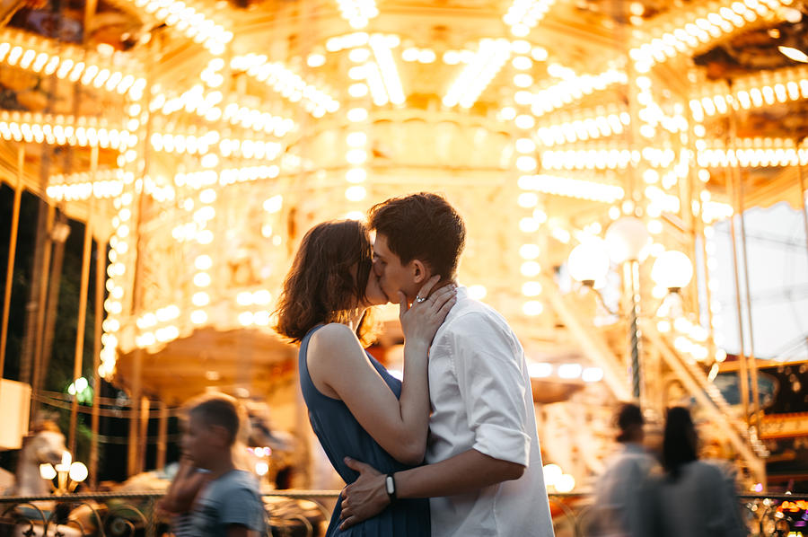 Couple kissing near the marry-go-round in the park Photograph by Igor Ustynskyy