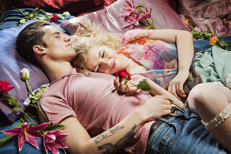 Couple laying on bed surrounded by flowers. Photograph by Betsie Van der Meer