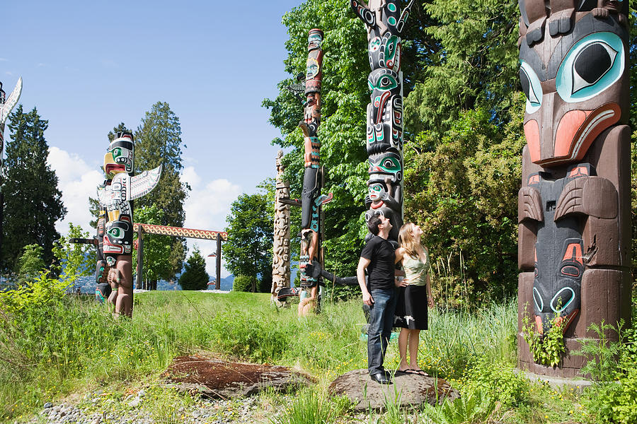 Couple looking at totem poles Photograph by Image Source