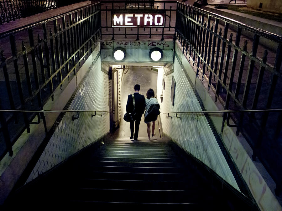 Couple of young people entering a station of the Paris Metro at night. Paris, France Photograph by Busà Photography