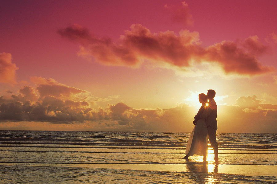 Couple posing on beach at sunset Photograph by Comstock