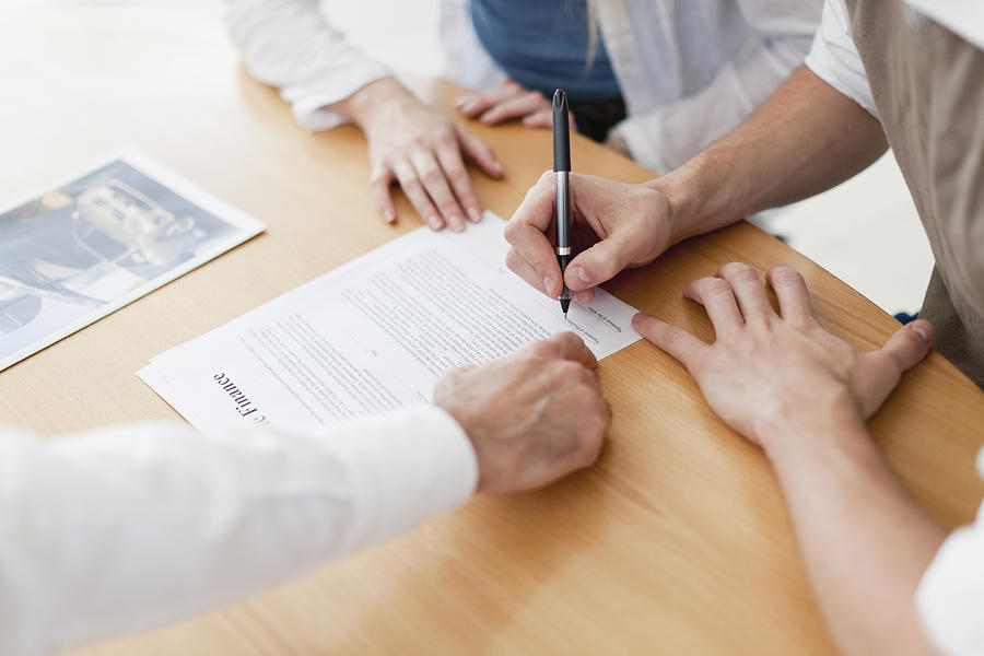 Couple signing contract with businessman Photograph by Photo_Concepts