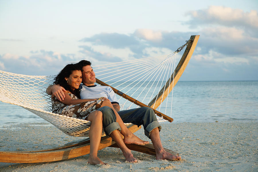 Couple smiling in hammock on beach, side view Photograph by Kraig Scarbinsky