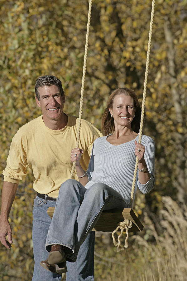 Couple swinging Photograph by Comstock Images