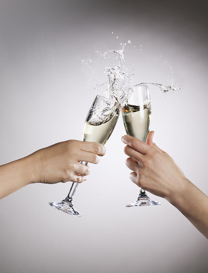 Couple toasting champagne flutes and spilling Photograph by Robert Daly