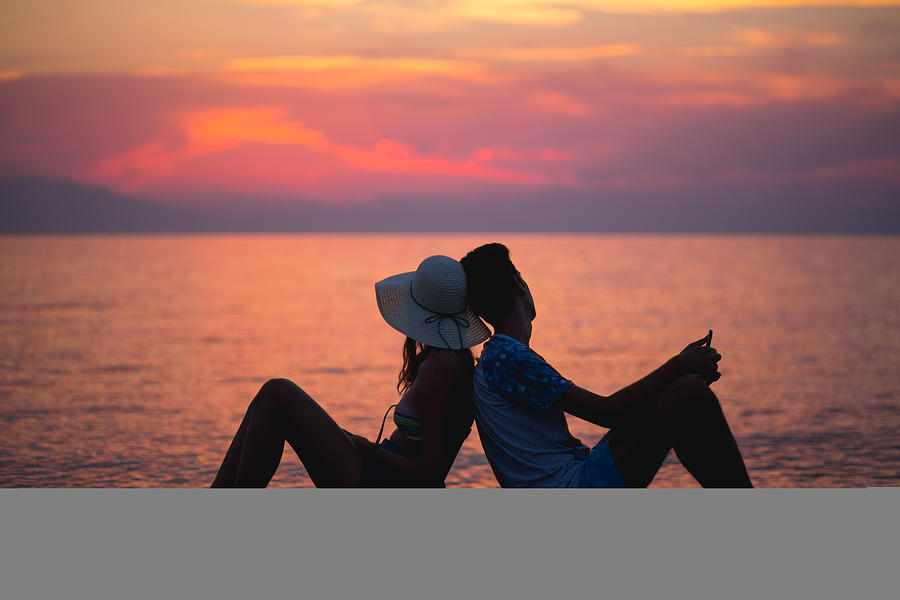 Couple Watching Sunset On The Beach Photograph by Constantinis