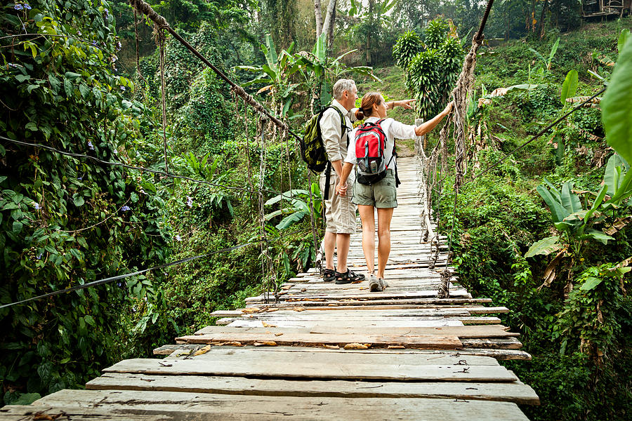 Couple with backpack hiking in rainforest Photograph by FredFroese