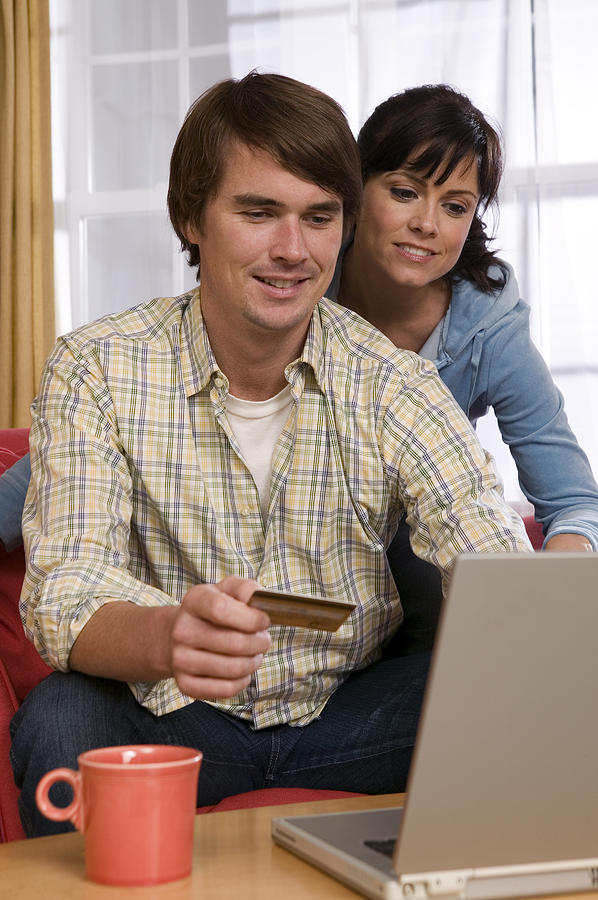 Couple with credit card using laptop Photograph by Comstock Images