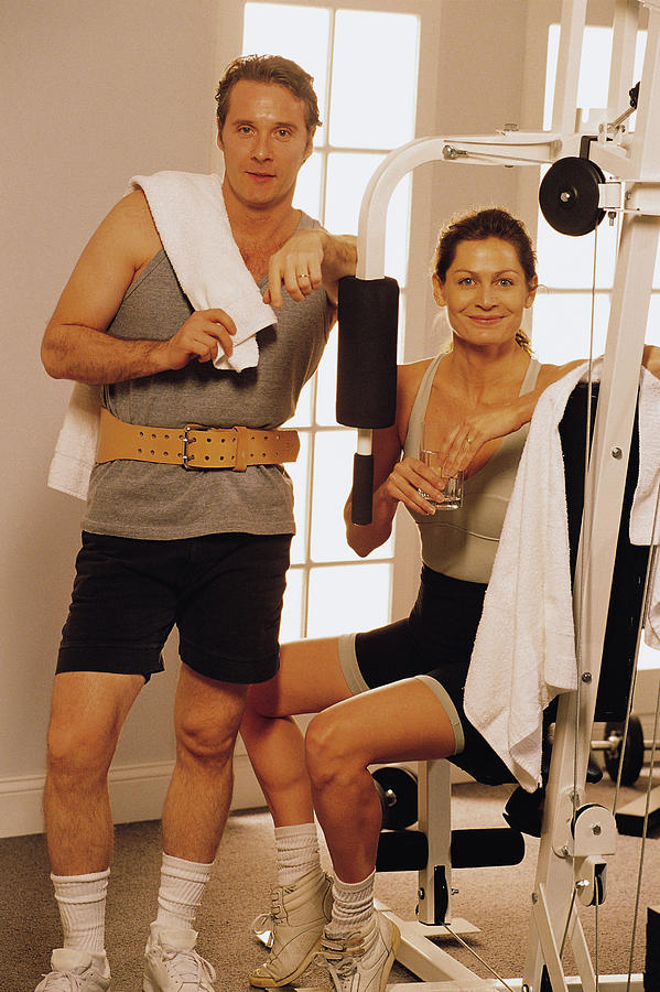 Couple with exercise equipment at health club Photograph by Comstock