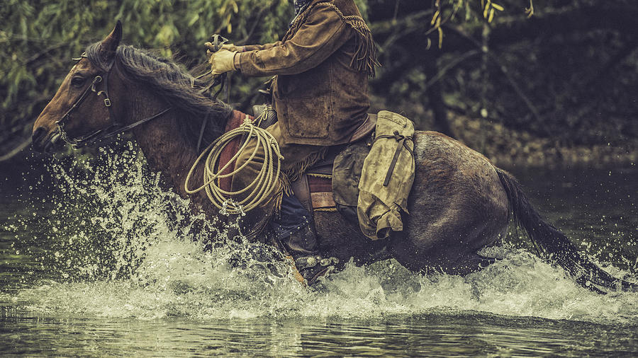 Cowboy on a horse riding across a river Photograph by Vm