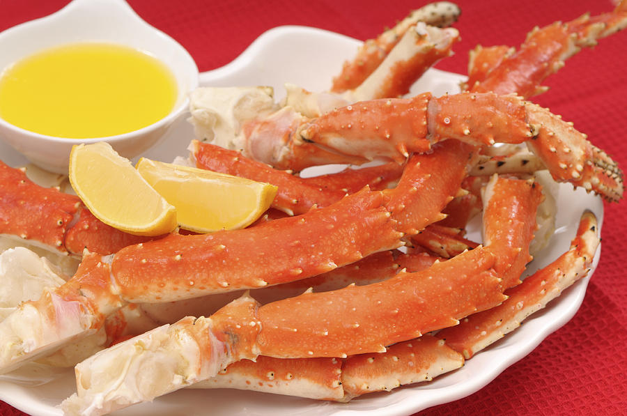 Crab legs served with lemon and butter Photograph by CreativeI