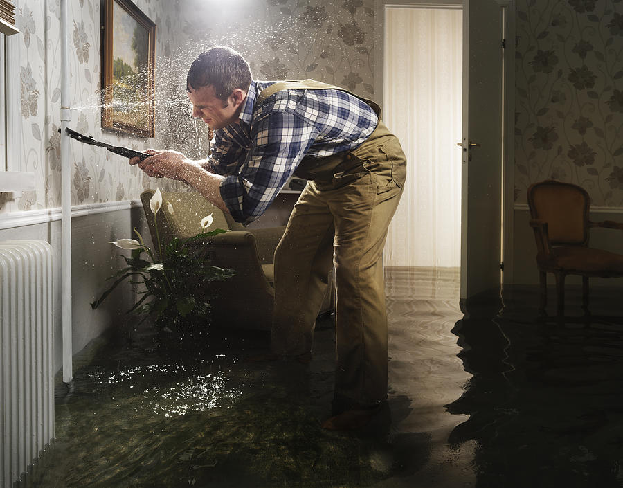 Craftsman Fixing Pipe In Flooded Room Photograph by Henrik Sorensen