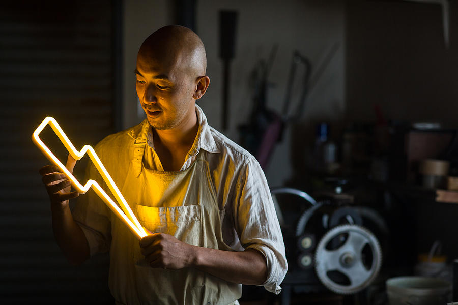 Craftsmen holding a lightning bolt shaped neon light Photograph by Trevor Williams