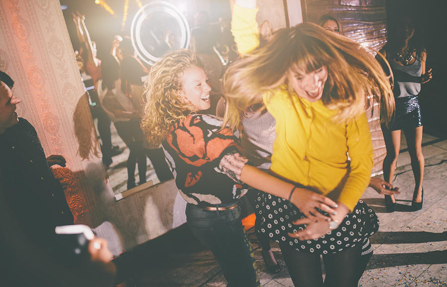 Crazy friends dancing wildly at a party in a club Photograph by Wundervisuals