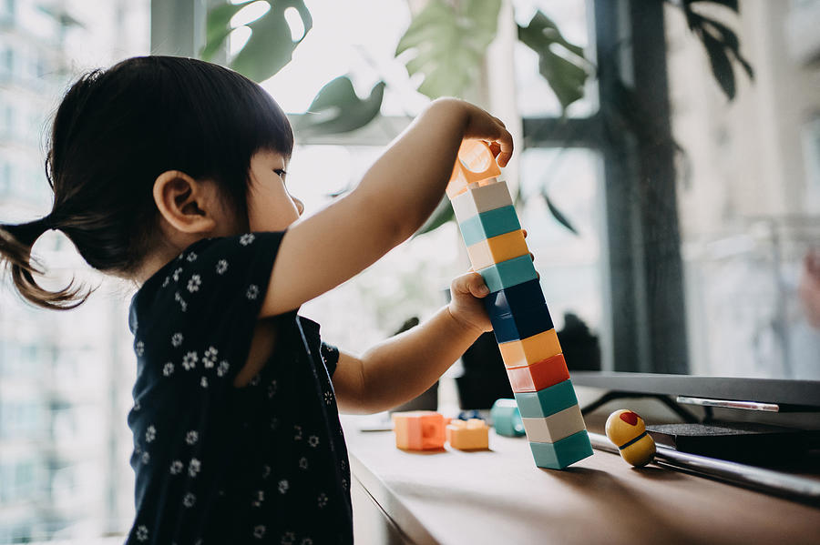 Creative little toddler girl playing with colourful building blocks at home Photograph by D3sign