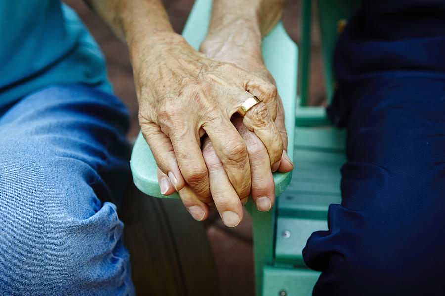 Cropped close up of senior couple hands holding on park bench Photograph by Kathleen Finlay