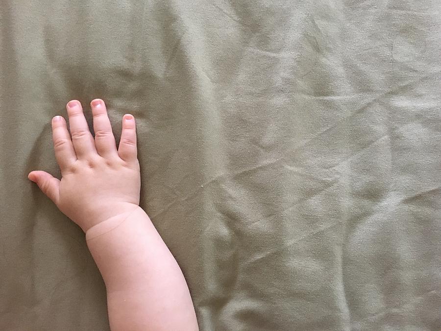 Cropped Hand Of Baby On Bed Photograph by Lorenzo Garassino / EyeEm