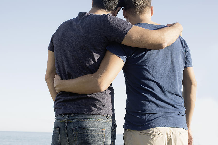 Cropped shot of mature male couple with arms around each other at coast Photograph by Gary John Norman