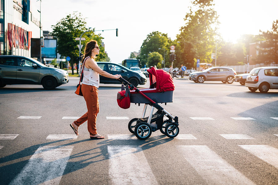 Crossing the boulevard with baby in prams with heavy traffic in rush hour Photograph by Drazen_