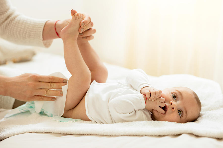 Cute baby in bedroom getting diaper changed. Photograph by Skynesher