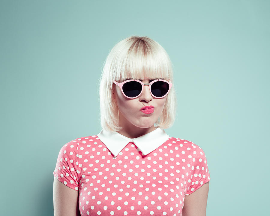 Cute blonde young woman wearing polka dotted dress making faces Photograph by Izusek