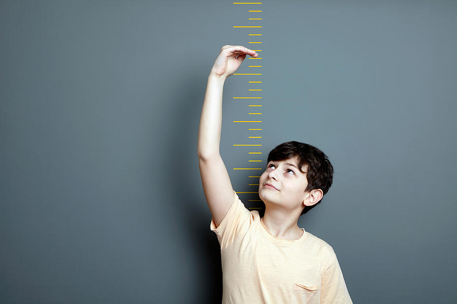 Cute boy is showing height on a wall scale Photograph by Xefstock