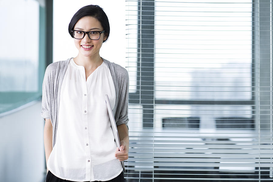 Cute businesswoman with glasses in the office Photograph by BJI / Blue Jean Images