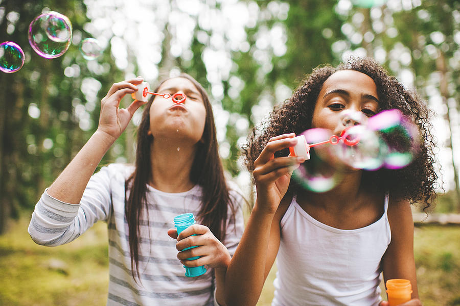 Cute girls blowing bubbles outdoors Photograph by Knape