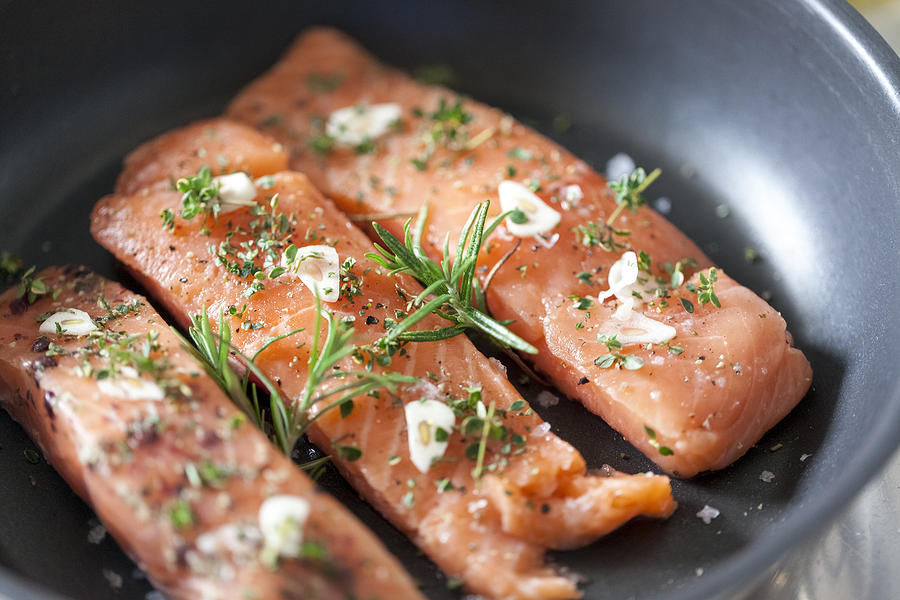 Delicious salmon fillet in a pan with garlic and herbs Photograph by Malorny