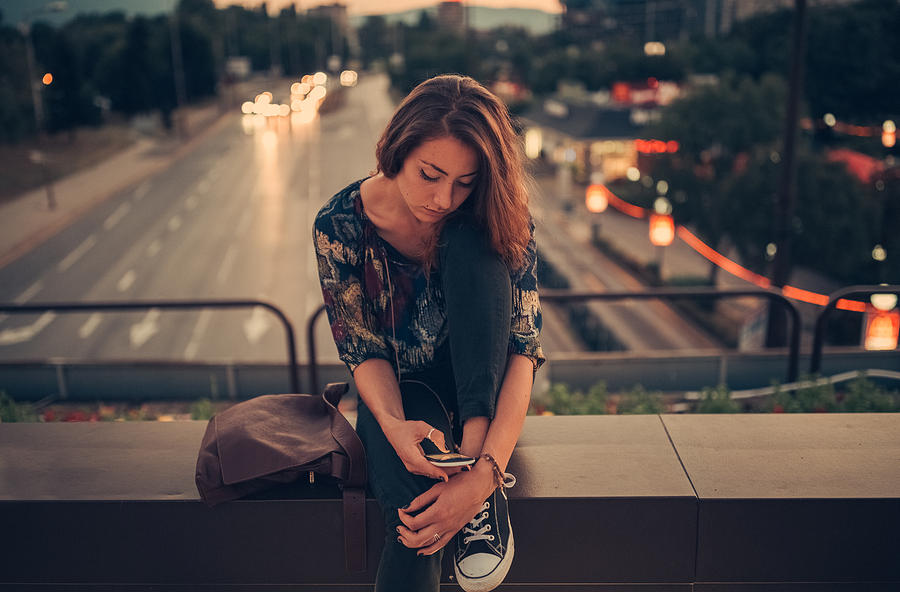Depressed teenage girl texting on the bridge Photograph by Martin-dm