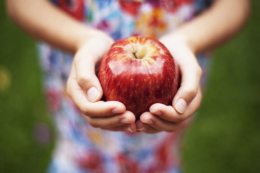 Depth of field apple held by a girl in colored dress outside Photograph by Shaun