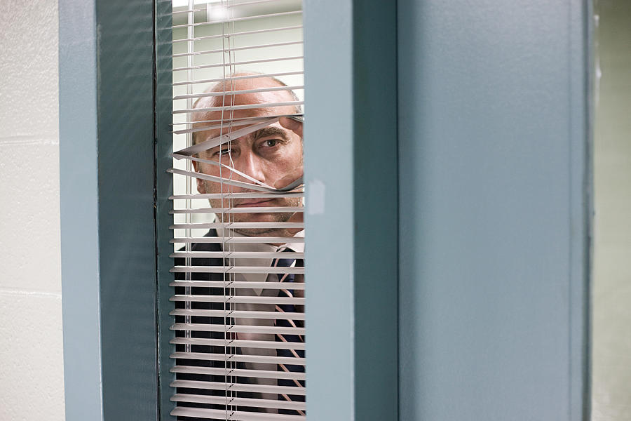 Detective looking through blinds Photograph by Image Source