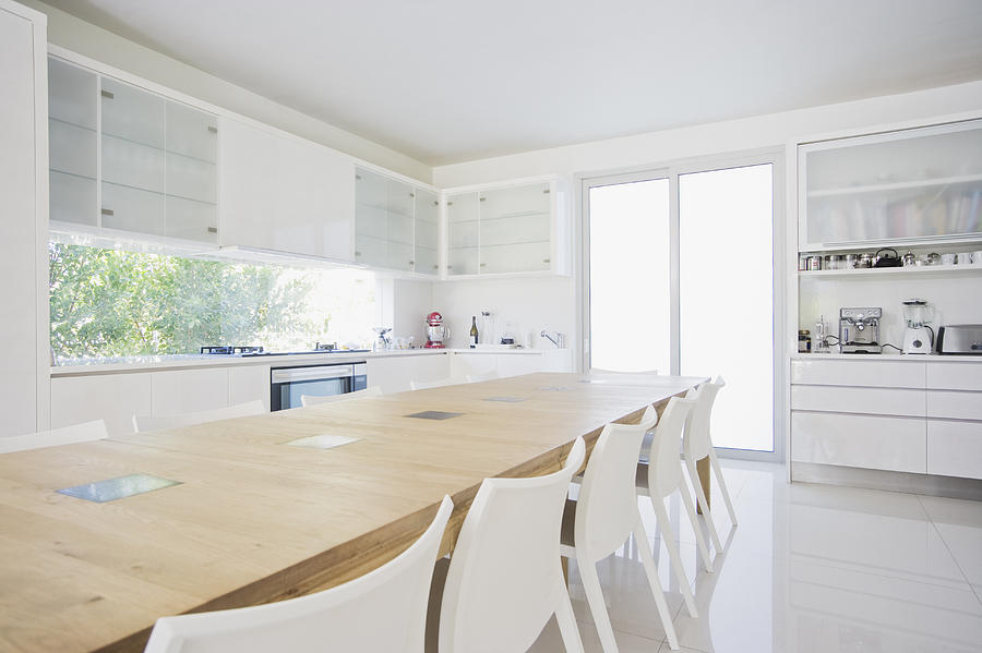 Dining table in modern, white kitchen Photograph by Robert Daly