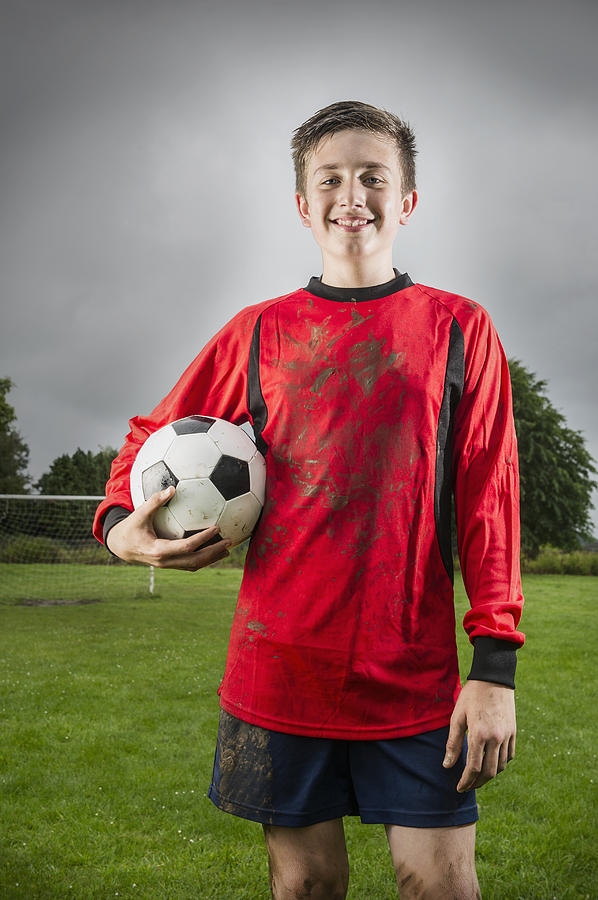 Dirty Caucasian soccer player holding ball on field Photograph by Jacobs Stock Photography Ltd