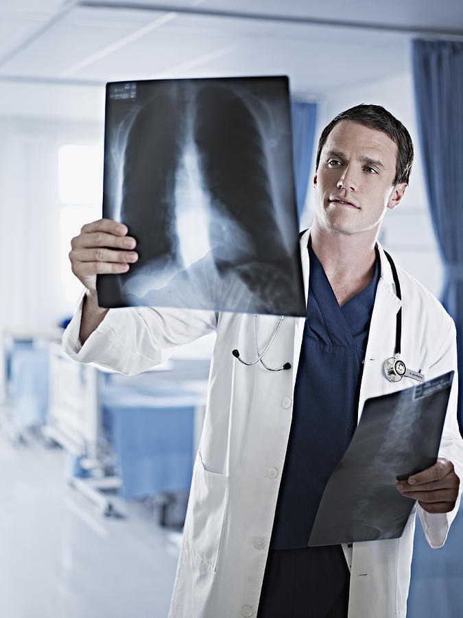 Doctor examining x-rays in hospital room Photograph by Chris Ryan