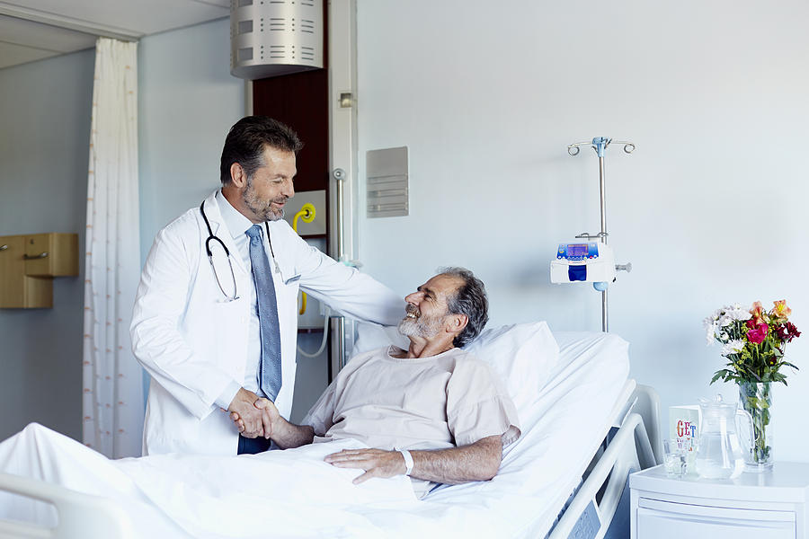 Doctor greeting patient in hospital ward Photograph by Morsa Images