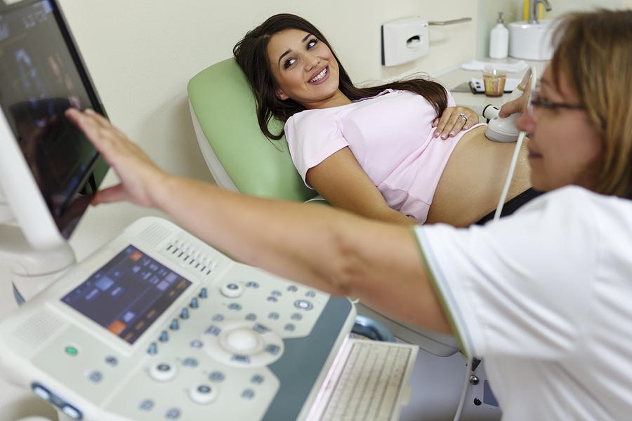 Doctor performing ultrasound on a pregnant woman Photograph by Damircudic