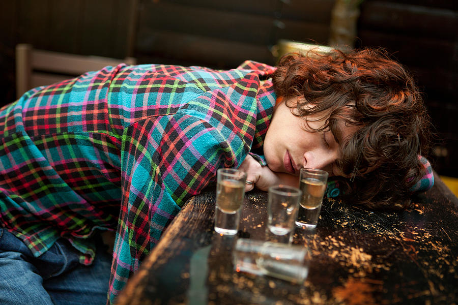 Drunk man slumped on bar asleep Photograph by Image Source