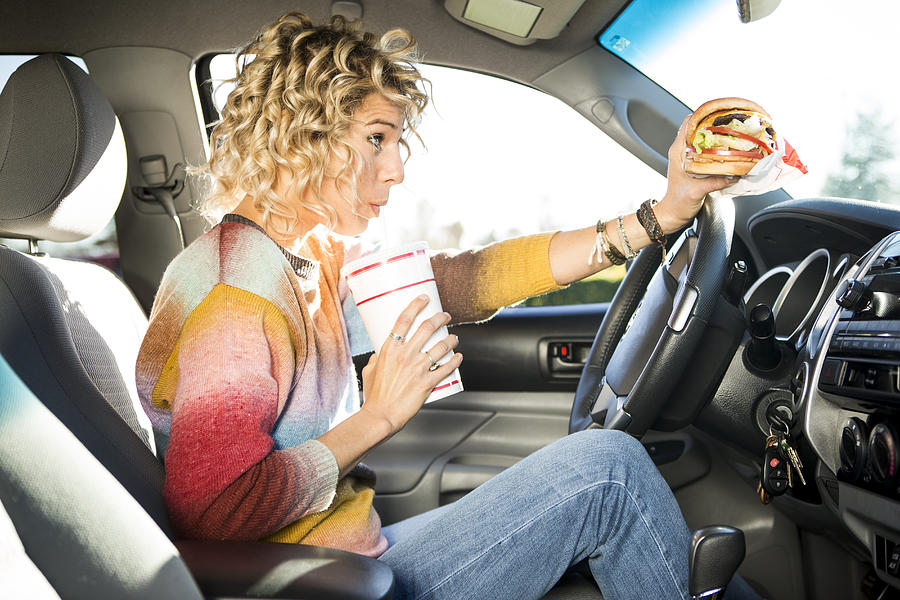 Eating fast food hamburgers and driving. Photograph by Jordan Siemens