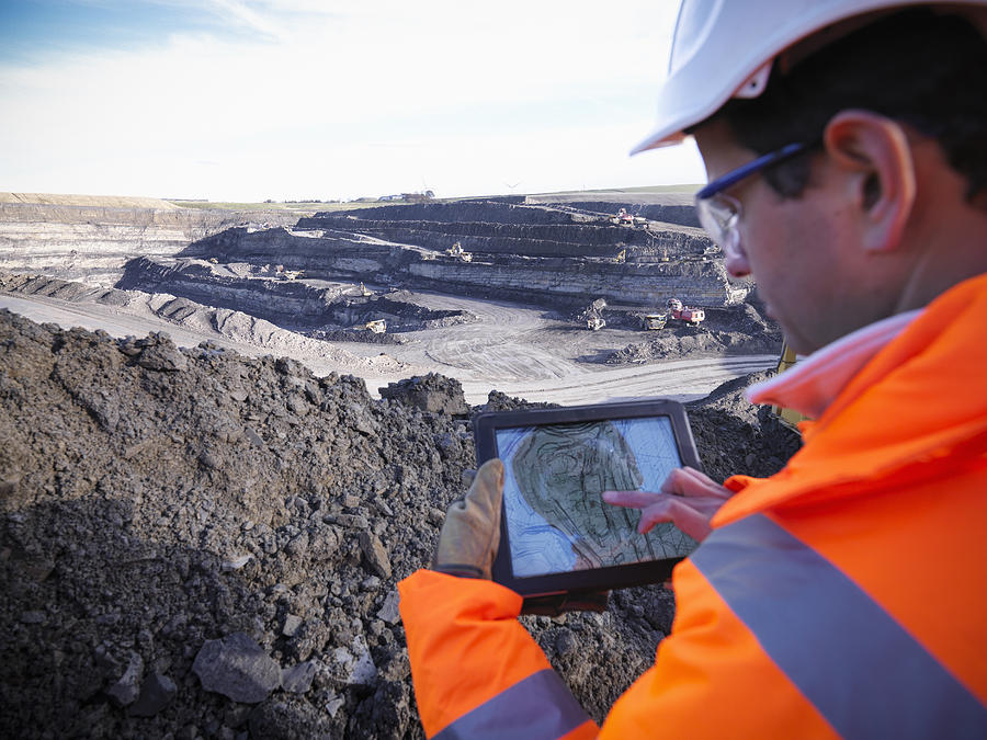 Ecologist using digital tablet surveying surface coal mine site, elevated view Photograph by Monty Rakusen