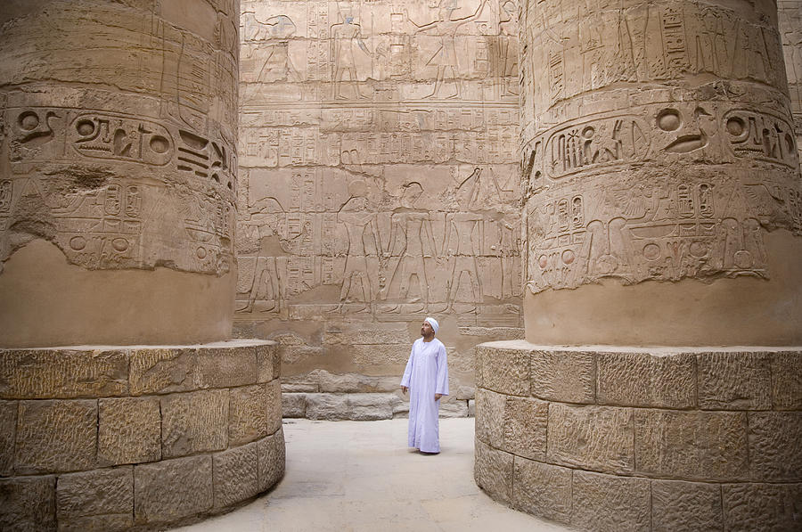 egyptian man standing in Karnak temple columns Photograph by Grant Faint