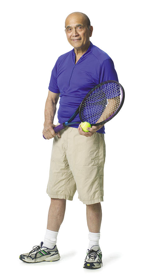 Elderly balding man wearing a blue shirt and holding a tennis racket smiling at the camera. Photograph by Photodisc