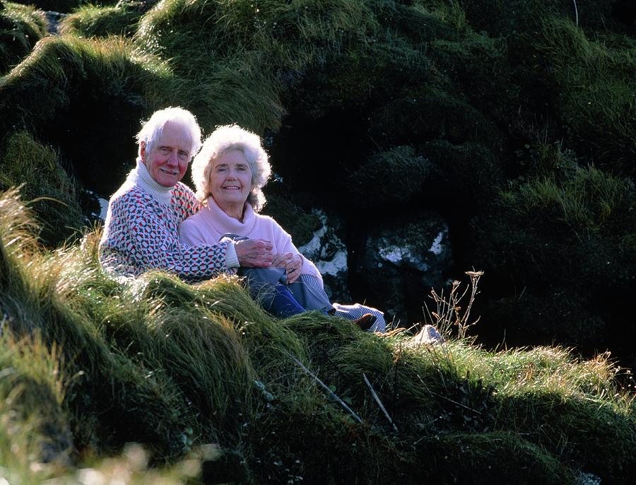 Elderly Couple On A Grassy Slope In Countryside Photograph by Ron Sutherland/science Photo Library
