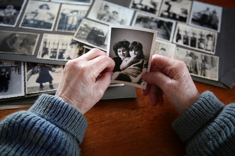 Elderly hands looking at old photos of self and family Photograph by Vasiliki