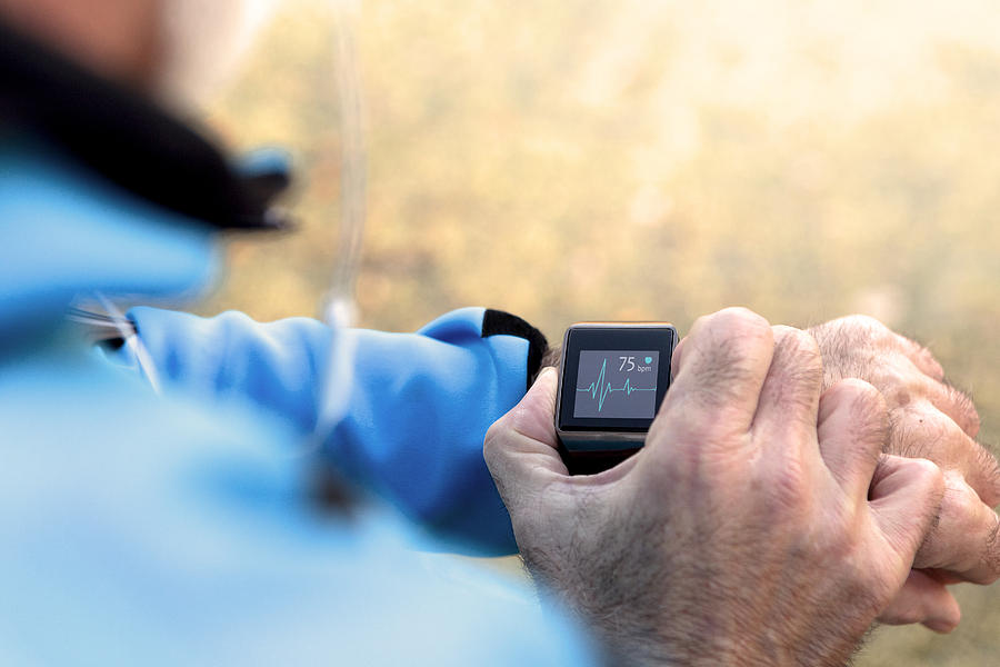 Elderly Man using Smart Watch measuring heart rate Photograph by Nastasic